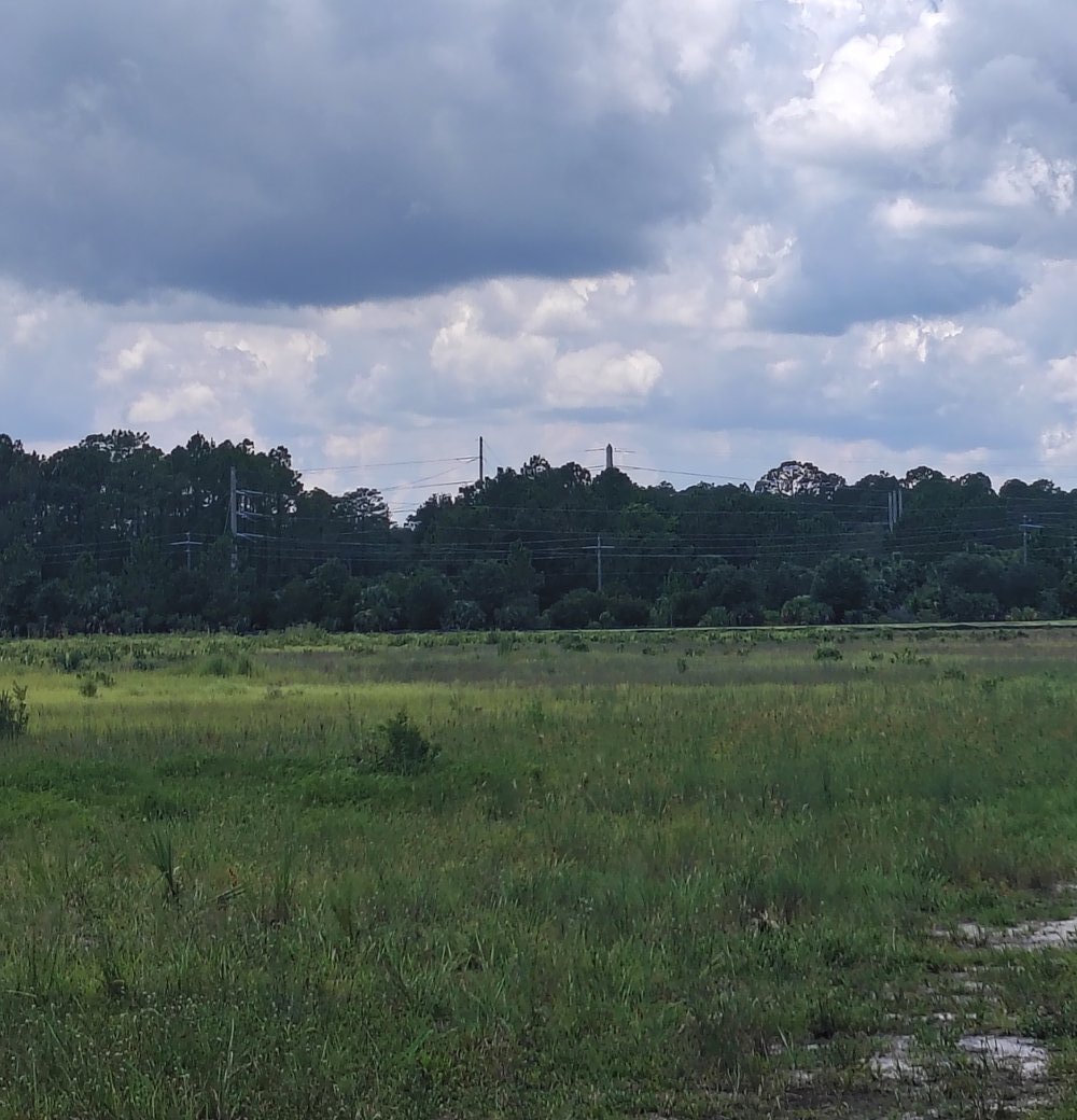 Open field at the far corner of the DC Blox property, with a fence marking the Google-owned parcel visible in the distance